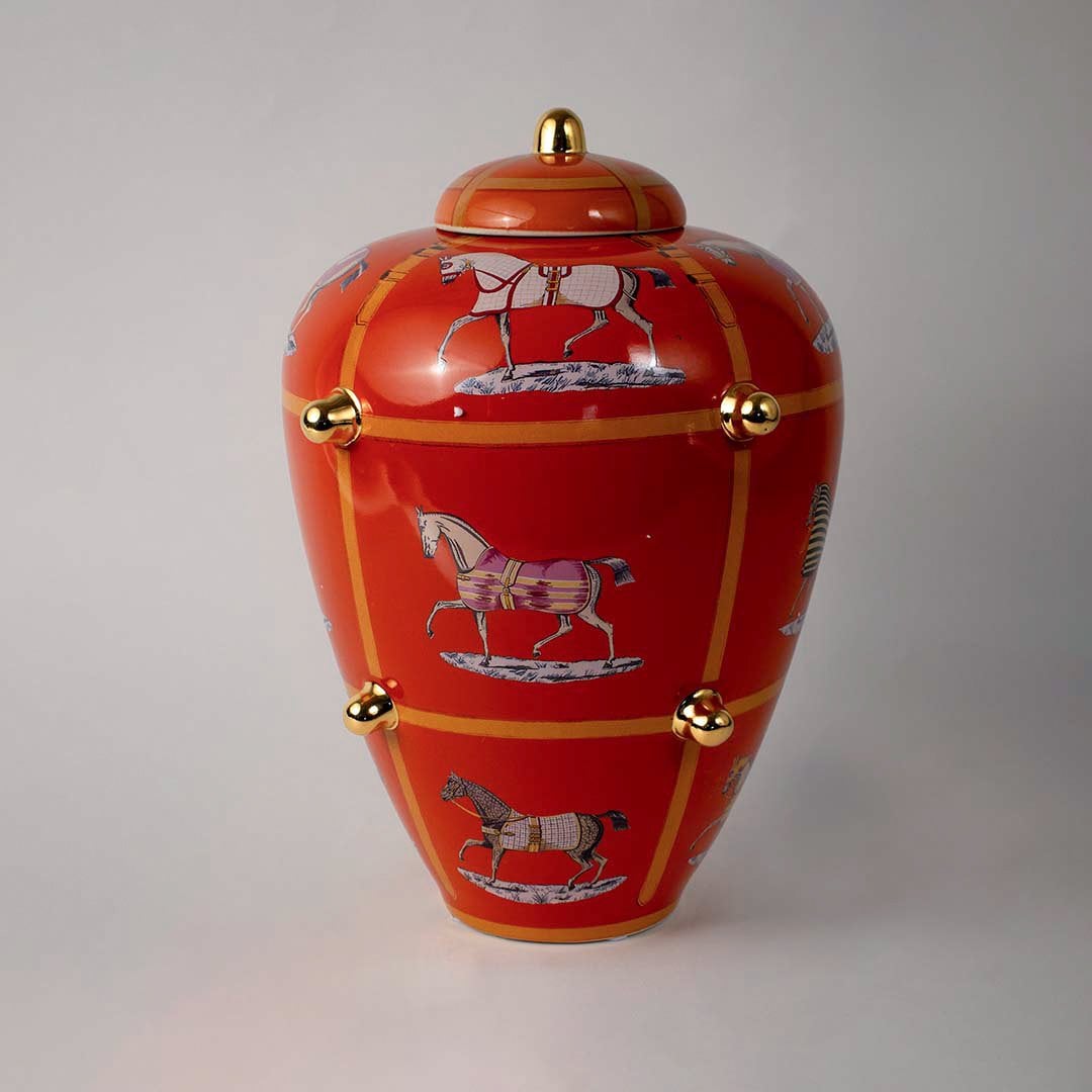 White background image ceramic ginger jar vase with bright orange finish horse motifs golden knobs elegant home decor.