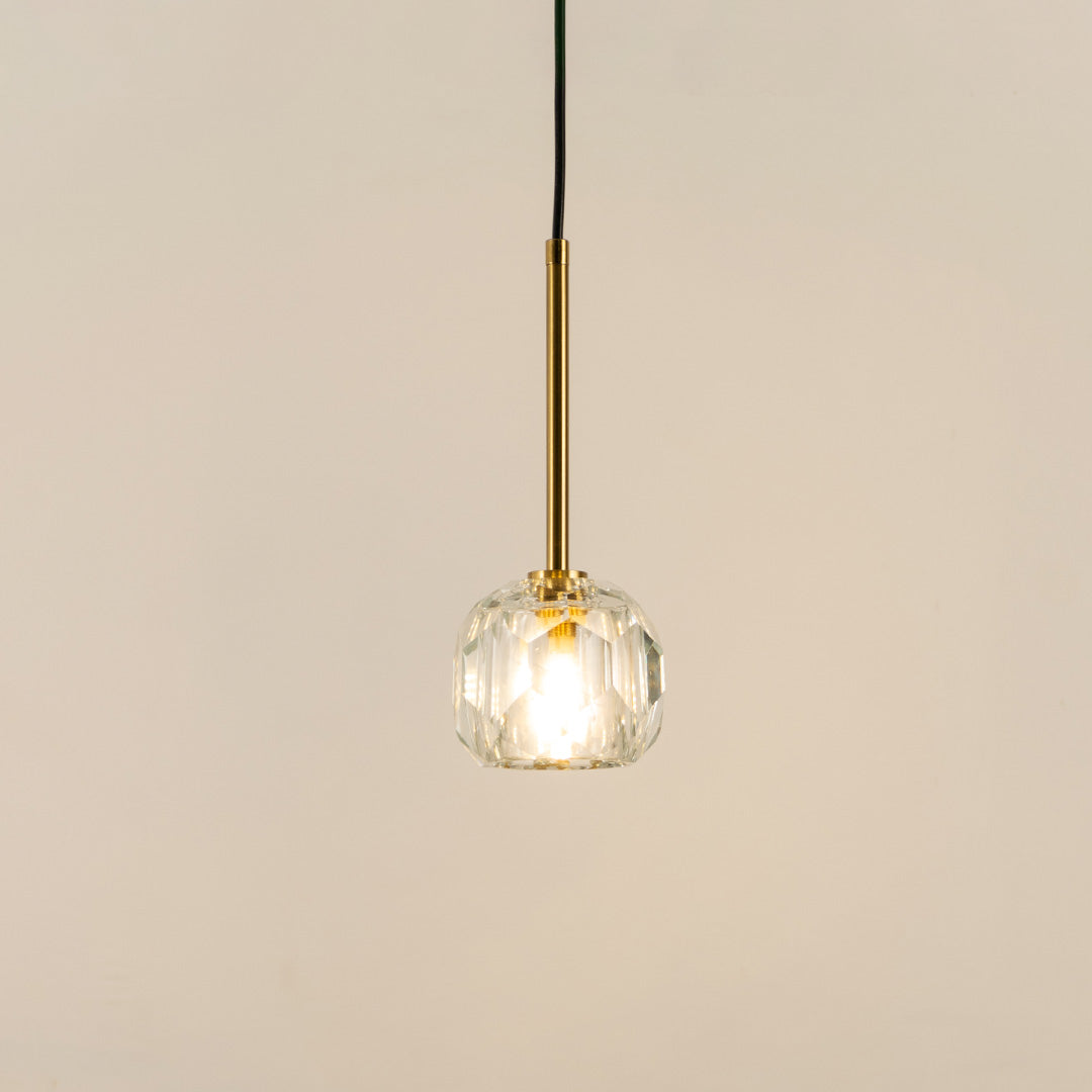 Illuminated clear textured glass pendant light with polished gold fittings for modern interiors.
