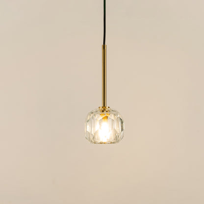 Illuminated clear textured glass pendant light with polished gold fittings for modern interiors.