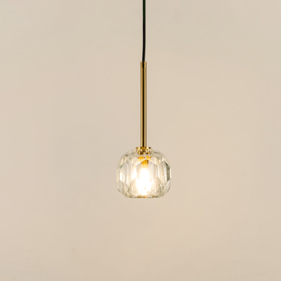 Illuminated clear textured glass pendant light with polished gold fittings for modern interiors.