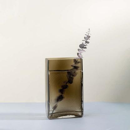 Ribbed glass vase in smoke brown rectangular design styled with dried flowers on rustic table against stone wall for vintage home decor.