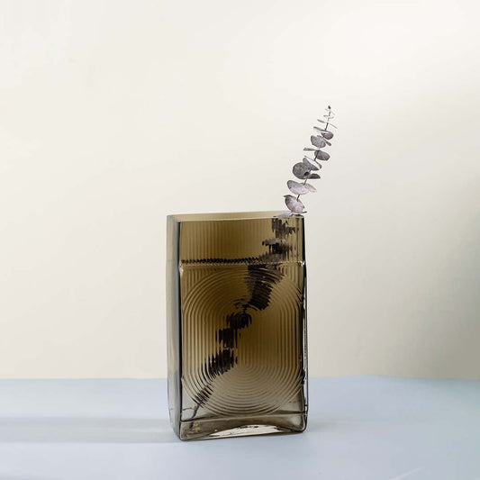 Ribbed glass vase in smoke brown rectangular design styled with dried flowers on rustic table against stone wall for vintage home decor.