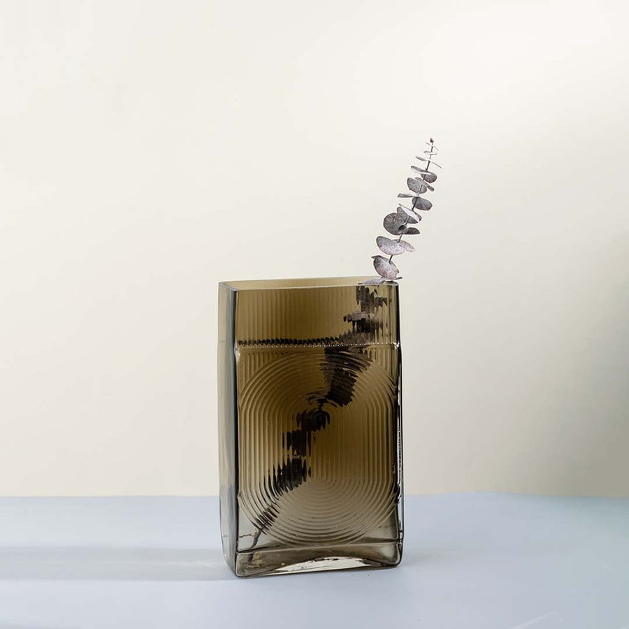 Ribbed glass vase in smoke brown rectangular design styled with dried flowers on rustic table against stone wall for vintage home decor.