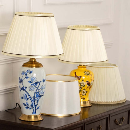 Table lamp set with elegant floral ceramic bases and pleated white shades placed on a dark wooden console in a classic interior setting