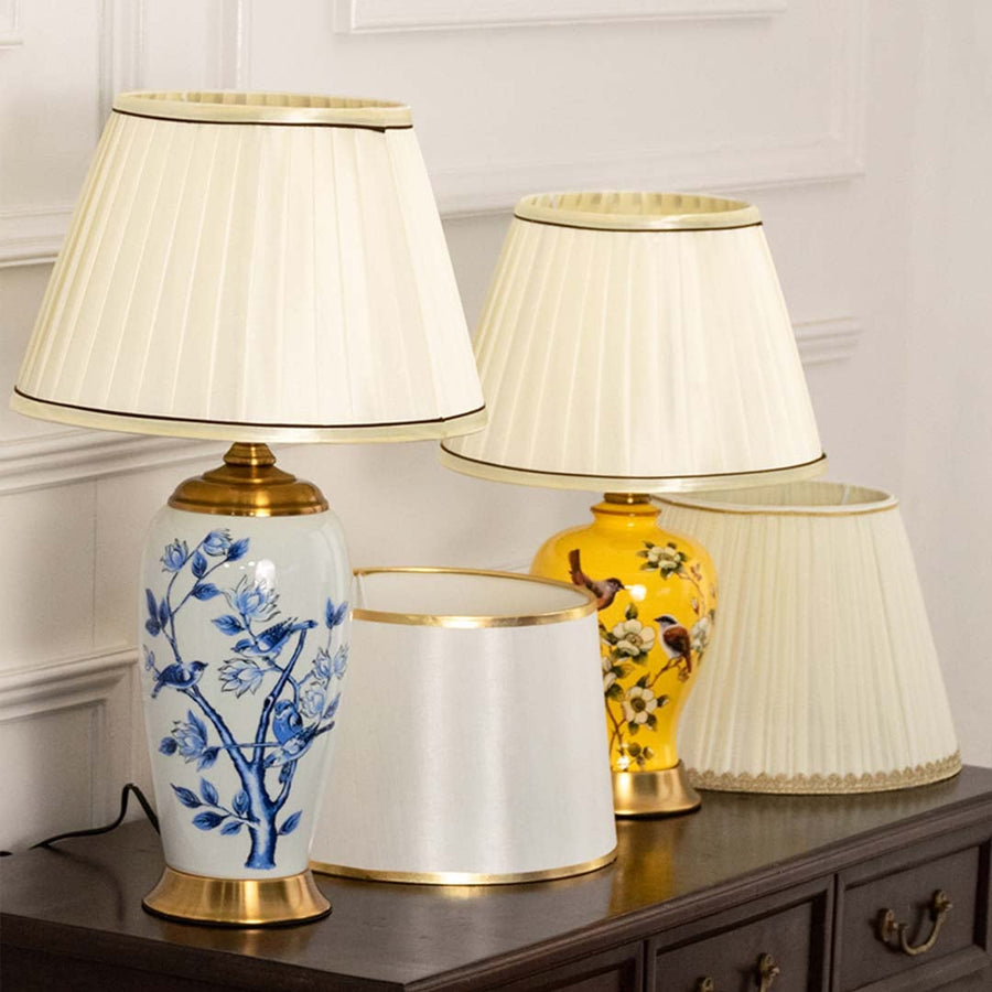 Table lamp set with elegant floral ceramic bases and pleated white shades placed on a dark wooden console in a classic interior setting