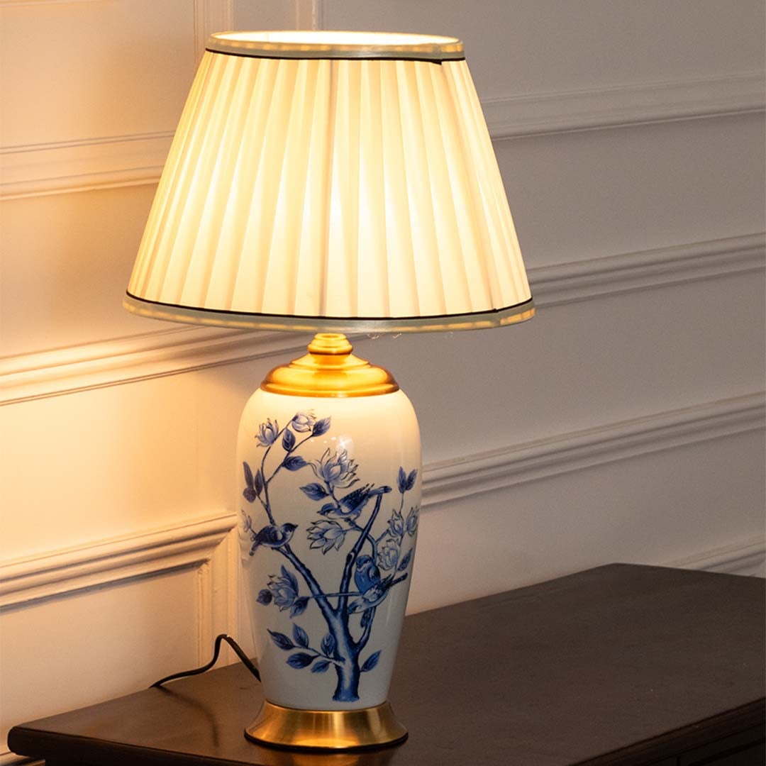 Ceramic table lamp with blue floral detailing and a cream pleated shade providing soft illumination ideal for traditional and modern interiors.