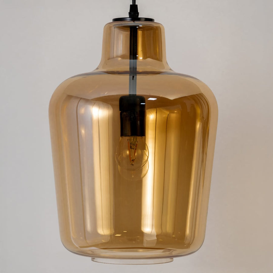 Closeup view of the amber pendant light highlighting the smooth glass finish warm glow and visible inner bulb detail