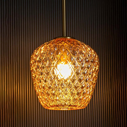 Textured amber glass pendant light displayed with light on against a dark backdrop enhancing its warm illumination and elegant artisan design.