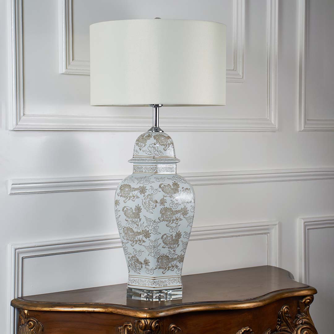 Ceramic table lamp with floral print base and white drum shade unlit on white background for interior decor table lamp.