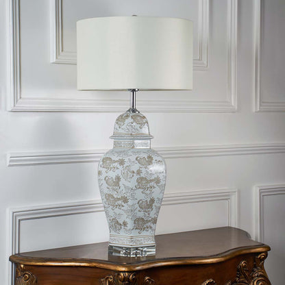 Ceramic table lamp with floral print base and white drum shade unlit on white background for interior decor table lamp.