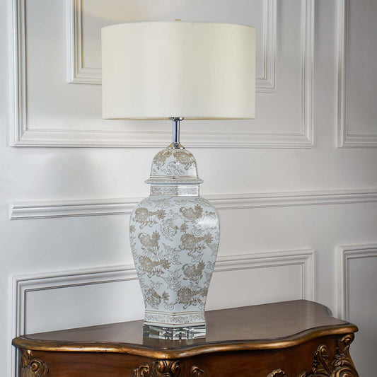 Clear etched glass table lamp with fabric shade displayed on a carved wooden console table creating elegant ambient lighting.