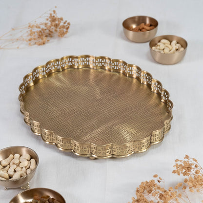 Gold finish brass plate with scalloped edge and textured base placed on white background for elegant serveware.
