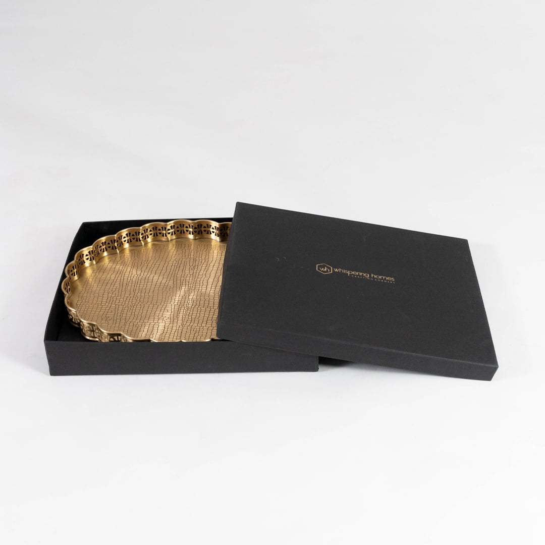 Elegant gold brass plate partially packed in premium black gift box with golden logo on a plain white backdrop.