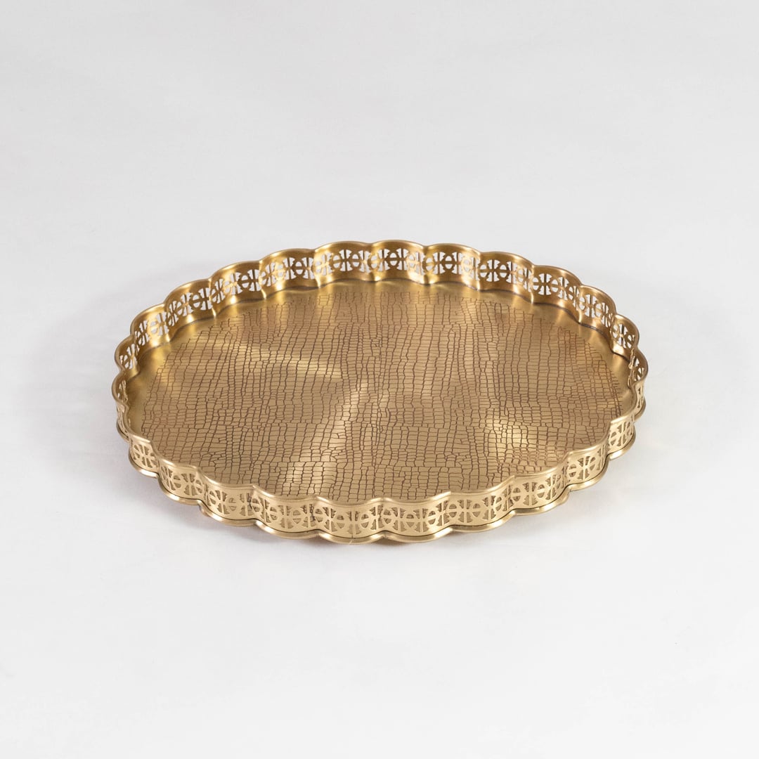 Gold finish brass plate with scalloped edge and textured base placed on white background for elegant serveware.