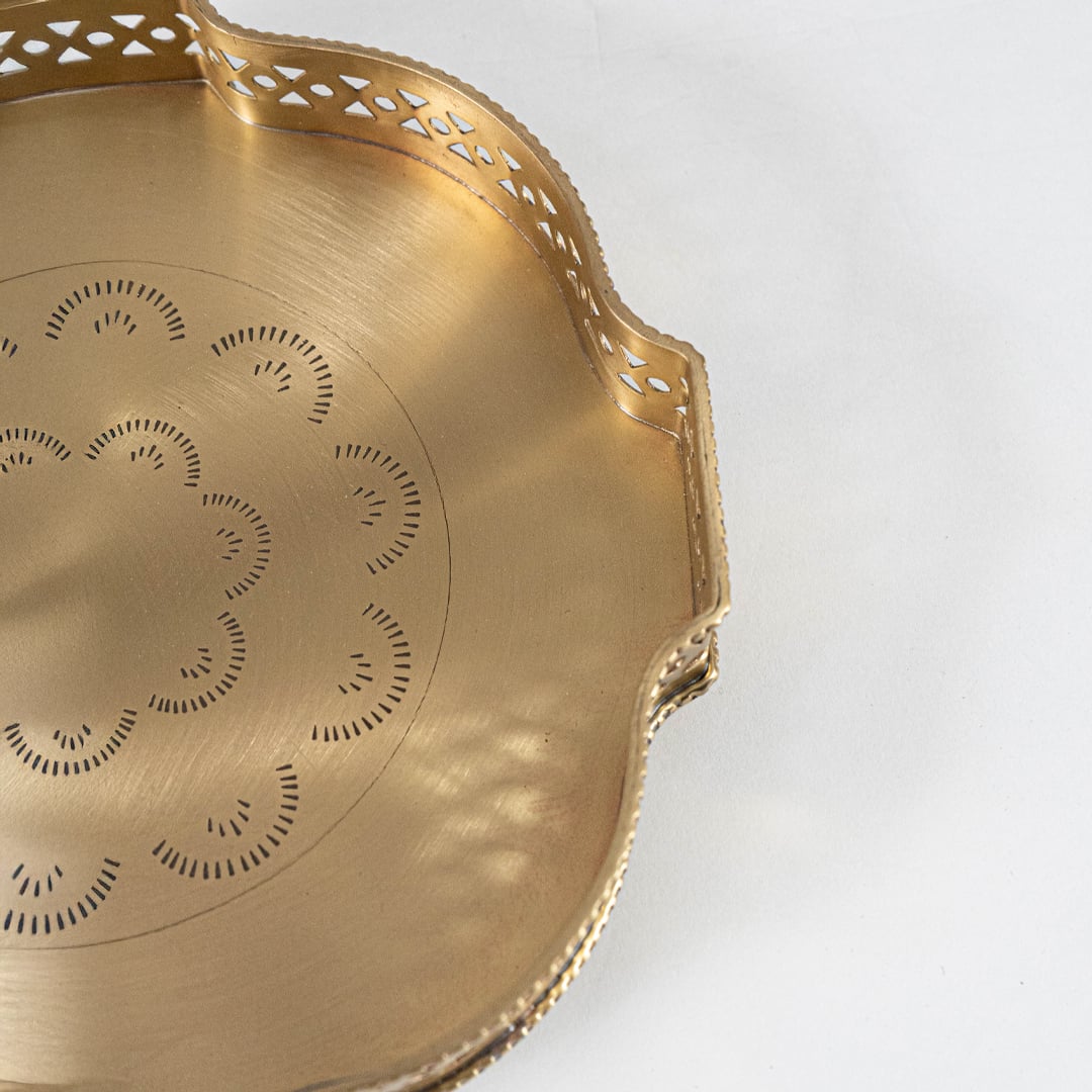 Closeup view of a golden diya tray showing detailed craftsmanship warm glow of lit tealights and rich textured metal finish creating an intimate festive feel.