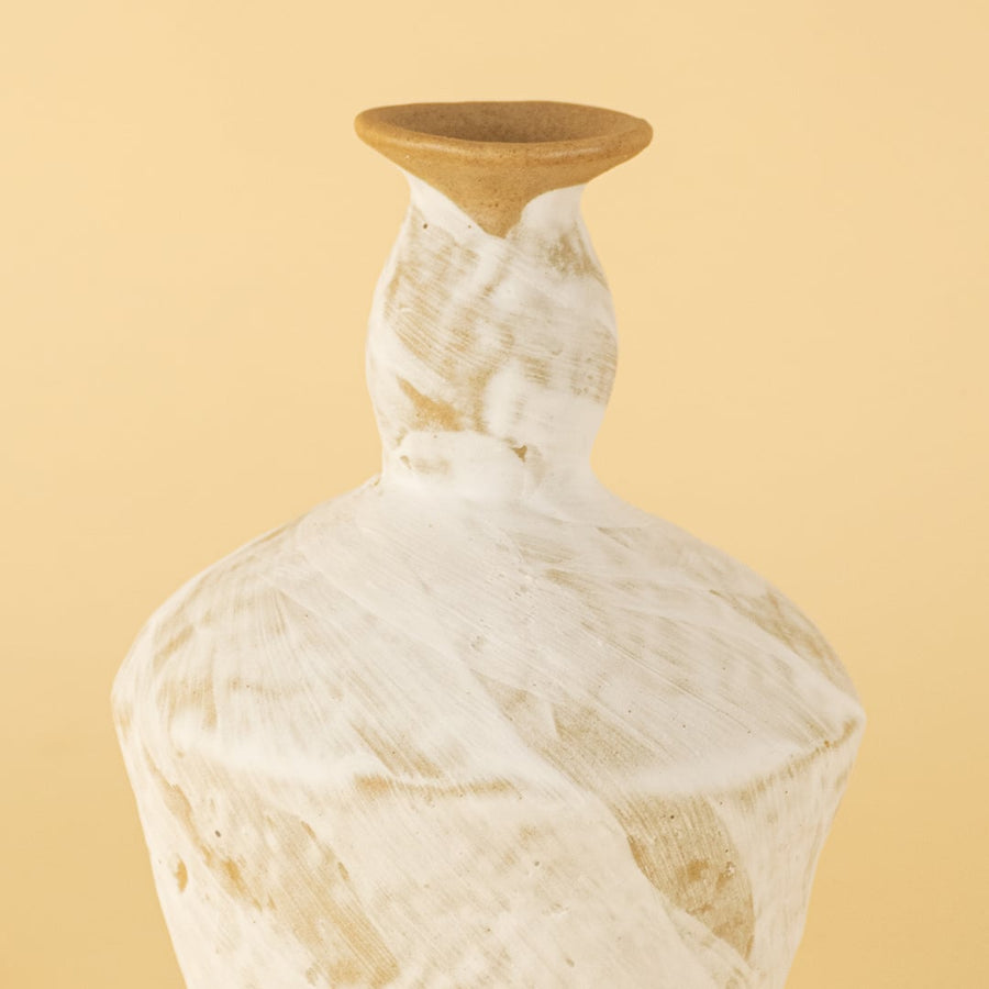 Closeup image of a handcrafted ceramic decorative vase featuring a whitewashed textured finish with natural earthy tones placed on a soft beige background highlighting artisanal surface details.
