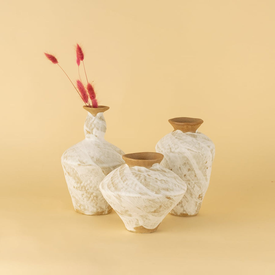 Set of handcrafted white and brown ceramic vases displayed together creating warm organic and artisanal decor styling.