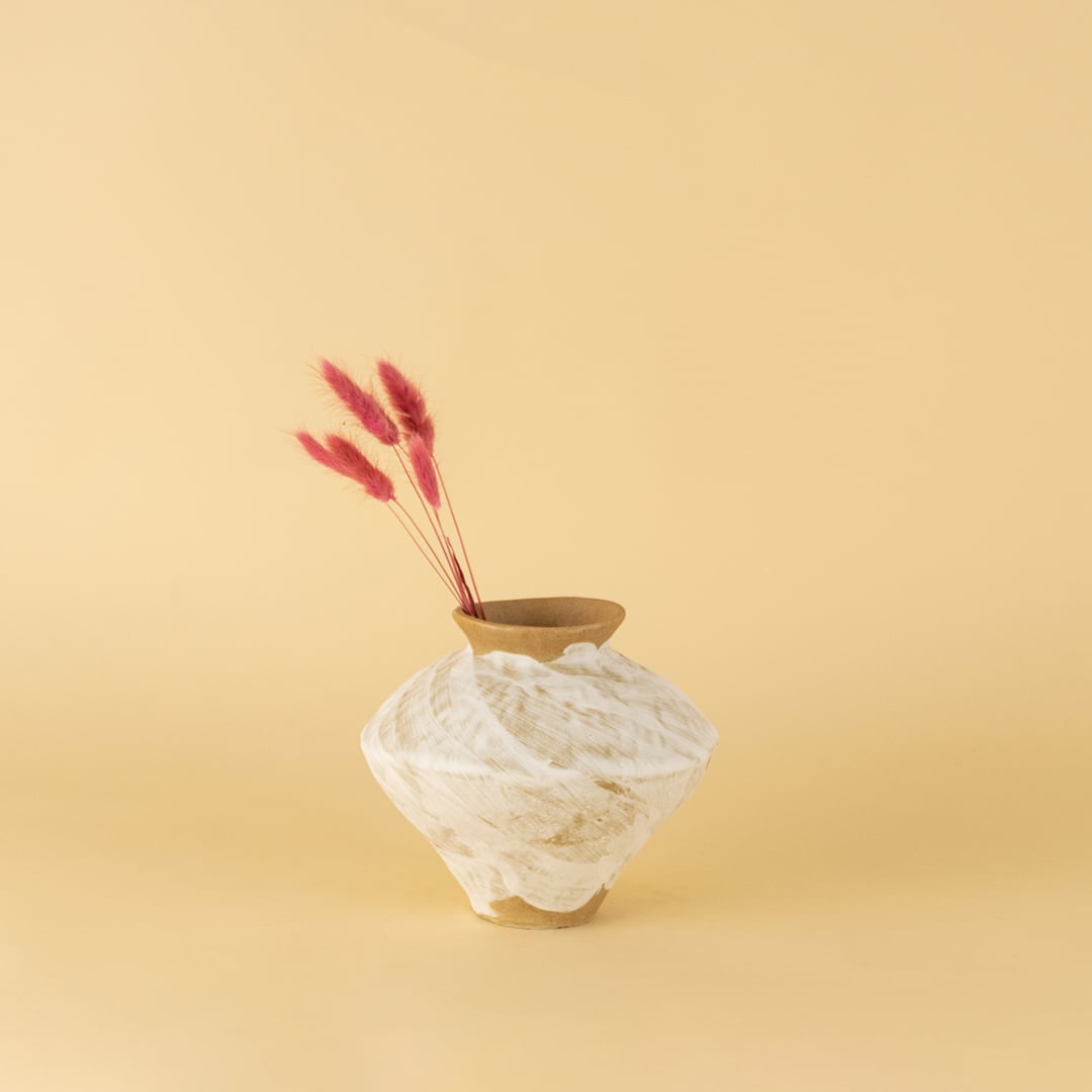 White and brown ceramic vase with rustic textured finish styled on table adding earthy charm to modern home decor.