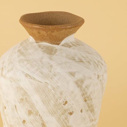 Handcrafted ceramic vase closeup showing sculpted neck and whitewashed textured finish with natural clay tones highlighted against a soft warm background.