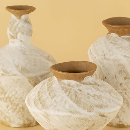 Detailed view of rustic ceramic vases in white and brown tones highlighting handmade texture and artistic surface
