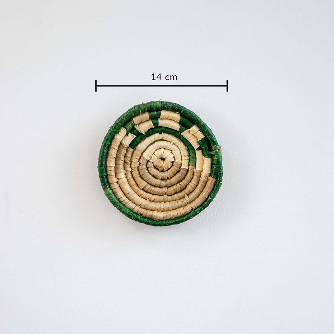 Small handwoven wall basket with green border and natural fiber center showing approx 20 cm diameter for compact wall styling.