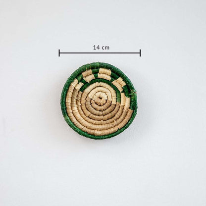 Small handwoven wall basket with green border and natural fiber center showing approx 20 cm diameter for compact wall styling.