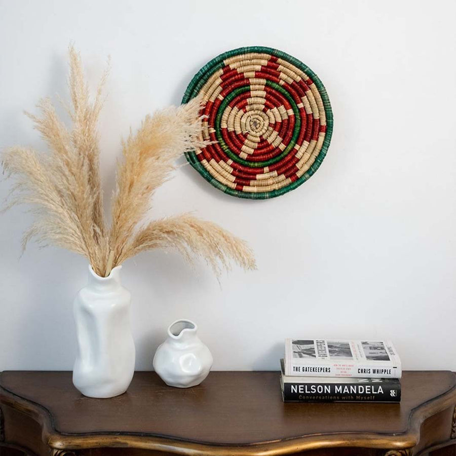 Red and green handwoven sabai grass wall basket styled on interior wall bringing colorful ethnic texture and statement decor appeal.