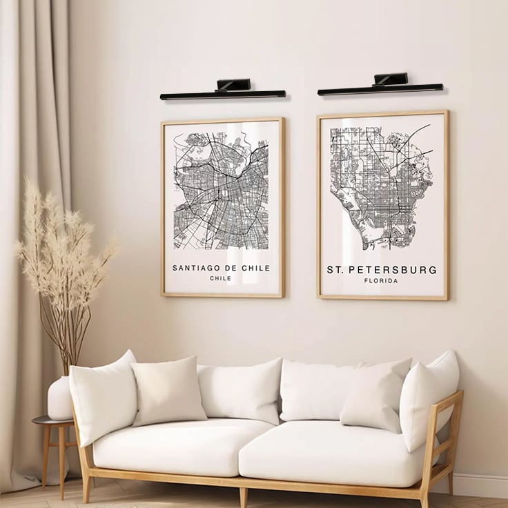 Black metal picture lights styled together on a modern interior wall creating warm balanced gallery style accent lighting.