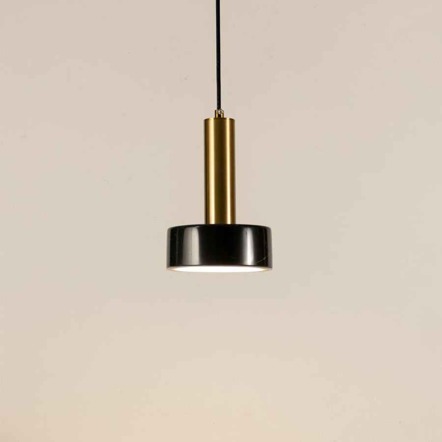 Black marble and metal round base pendant light hanging against plain background with light off for modern luxury décor.