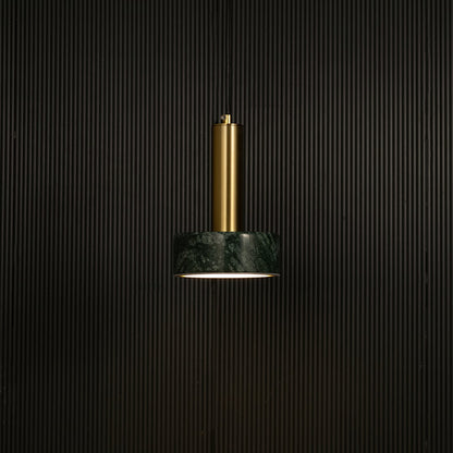 Green marble and metal round base pendant light hanging against dark textured wall with light off for premium modern décor.