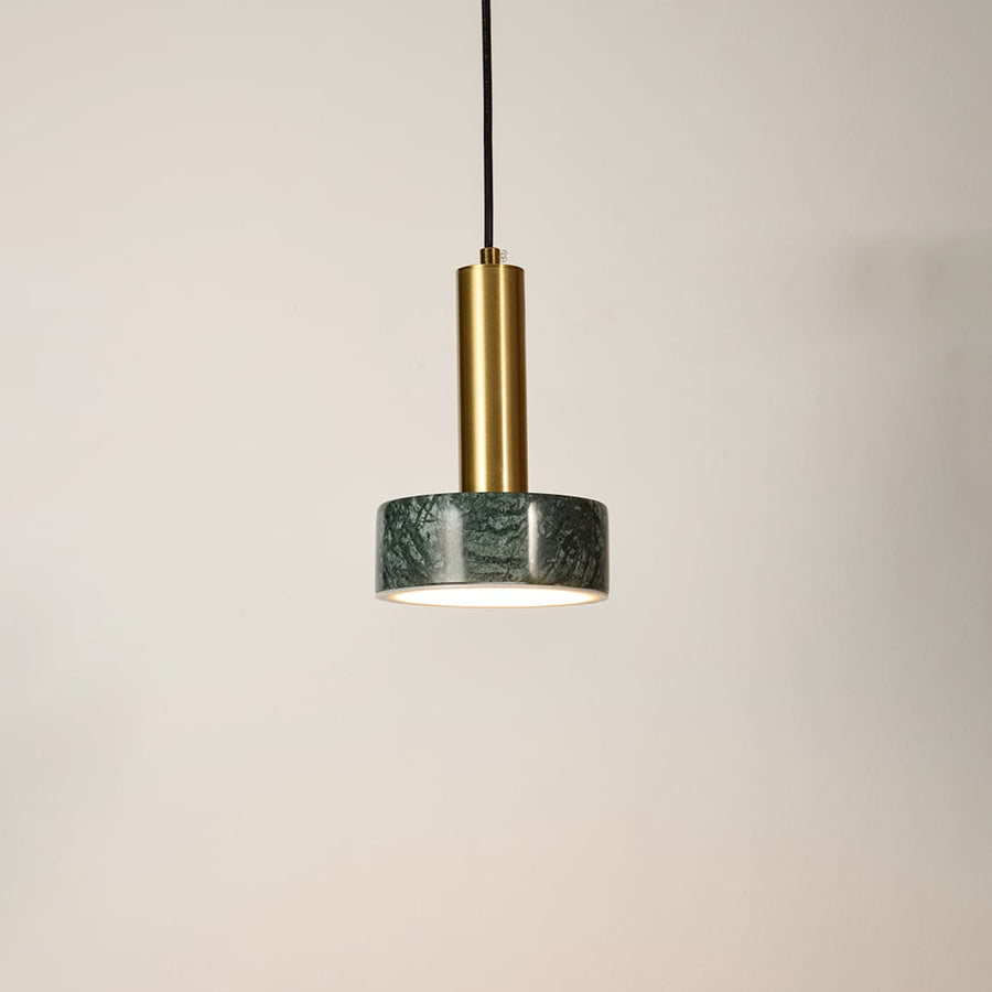 Green marble and metal round base pendant light hanging against plain background with light off for stylish modern décor.