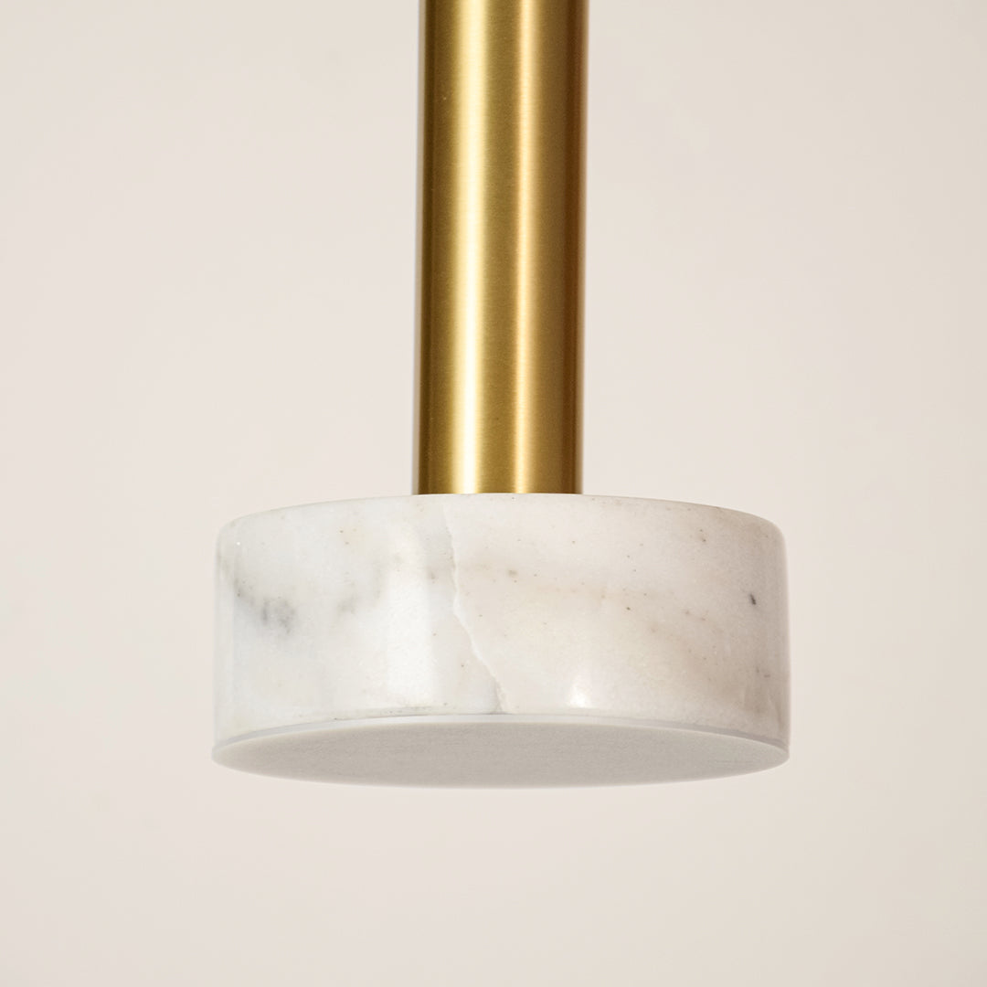 White marble and gold metal pendant light illuminated to showcase luxury ceiling lighting with elegant modern styling.
