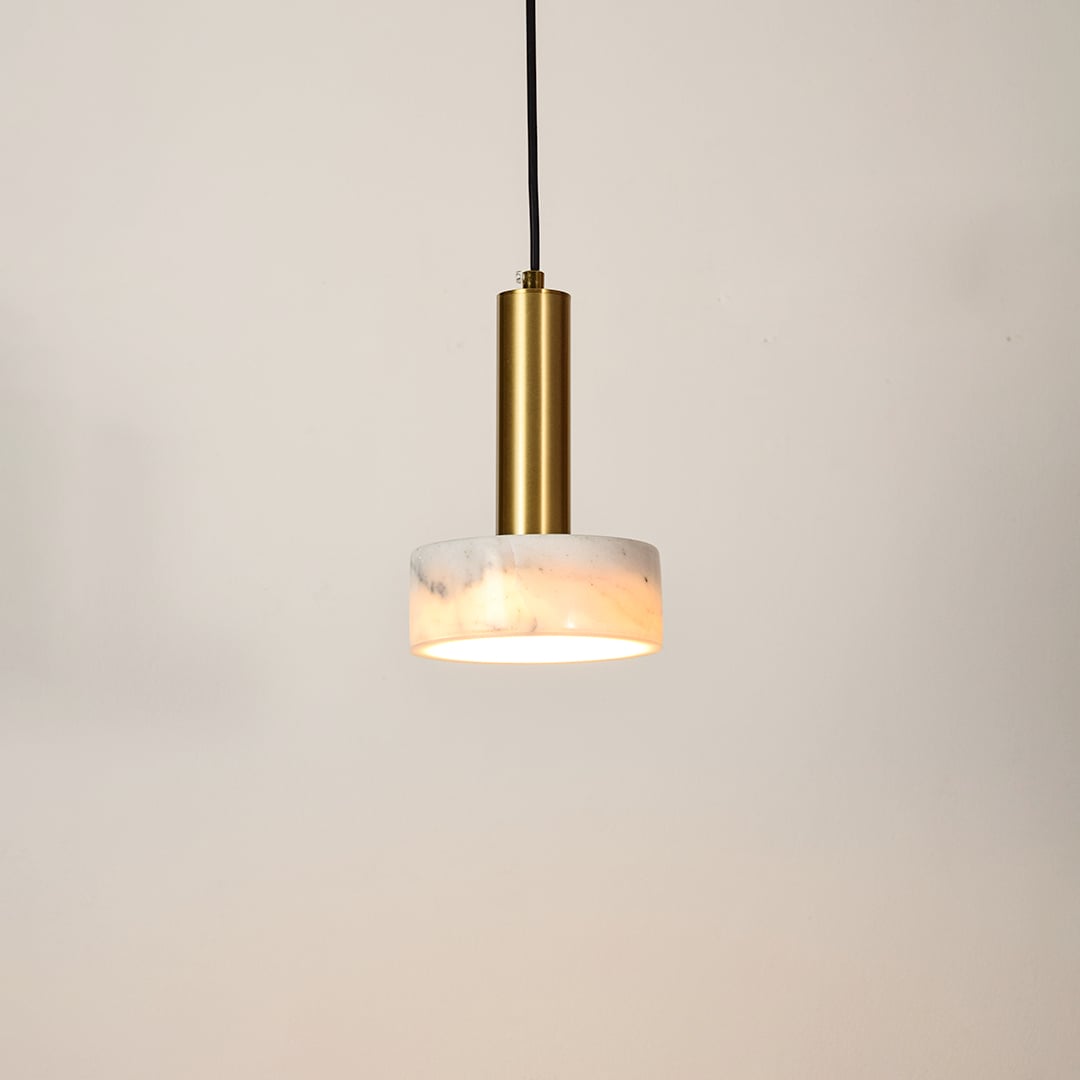 Gold metal pendant light with frosted glass diffuser illuminated to showcase modern ceiling lighting and warm glow.