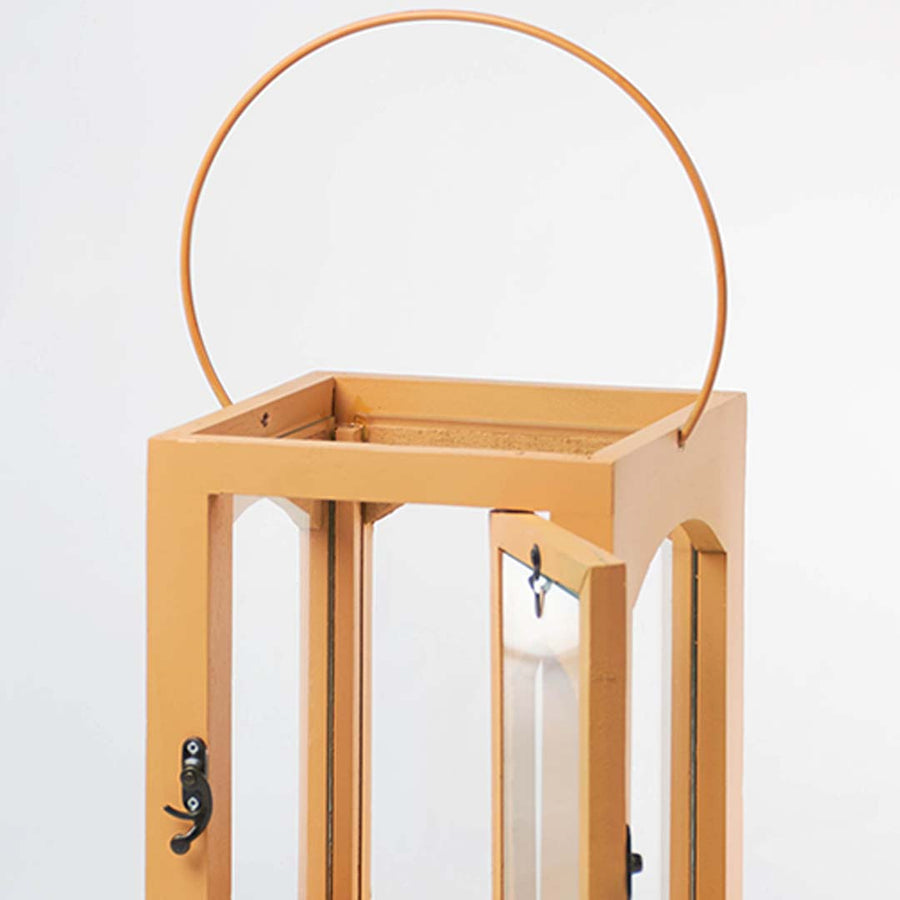 Closeup of wooden lantern with arch glass panels and metal handle for elegant decor styling use.