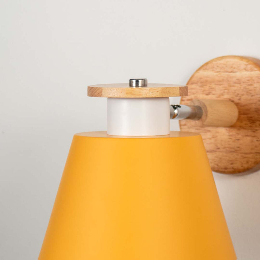 Closeup of mustard metal and wooden wall light for modern bedroom and elegant decor styling spaces.

