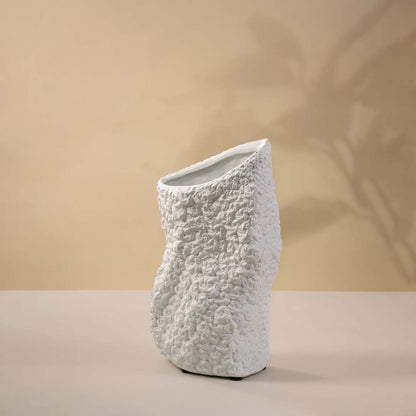Sculptural black textured ceramic vase with matte finish highlighted against white background for artistic depth.