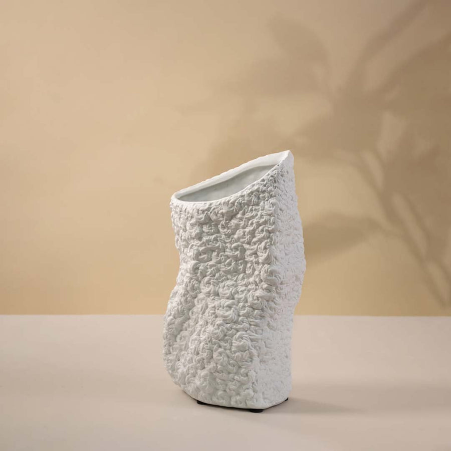 Sculptural black textured ceramic vase with matte finish highlighted against white background for artistic depth.