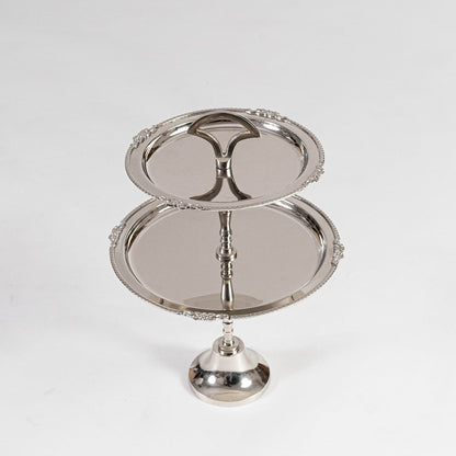 Disassembled silver metal two tier serving tray shown in a black branded box with lid partially open for packaging view.