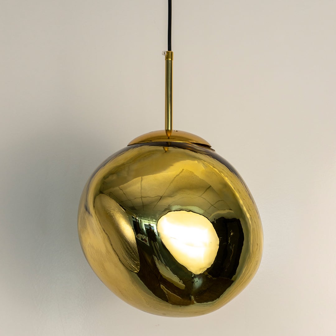Gold glass globe pendant light turned off with elegant metallic finish and brass-toned suspension rod shown against white background.