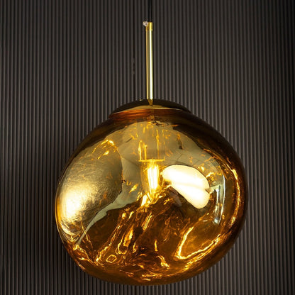 Gold glass globe pendant light casting a warm golden glow adding luxury and warmth to a black background.