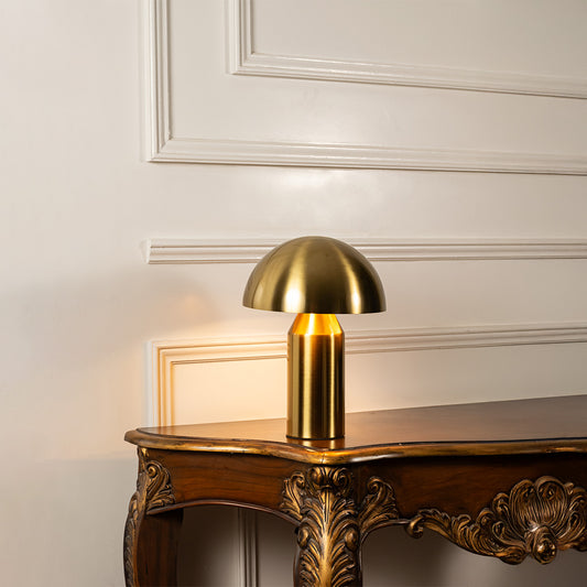 Gold metal mushroom table lamp displayed on a carved wooden console table creating elegant modern task lighting.