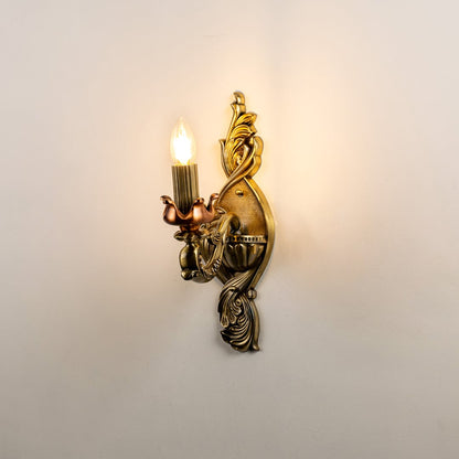 Decorative antique gold wall sconce with illuminated candle style bulb showcasing ornate carved detailing suitable for elegant classic interiors.