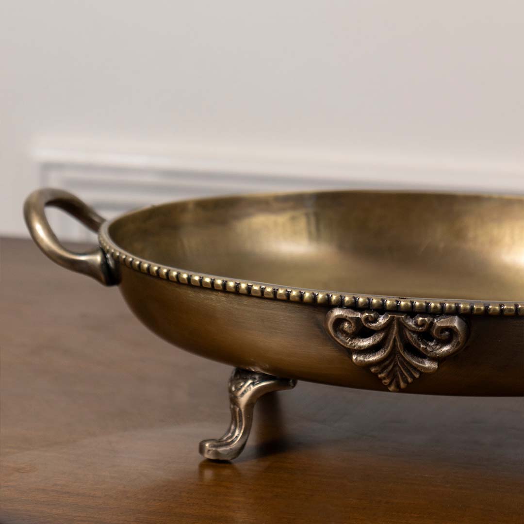 Closeup of brass decorative bowl with antique finish ornate detailing and footed base for luxury table decor home styling.