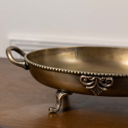 Closeup of brass decorative bowl with antique finish ornate detailing and footed base for luxury table decor home styling.