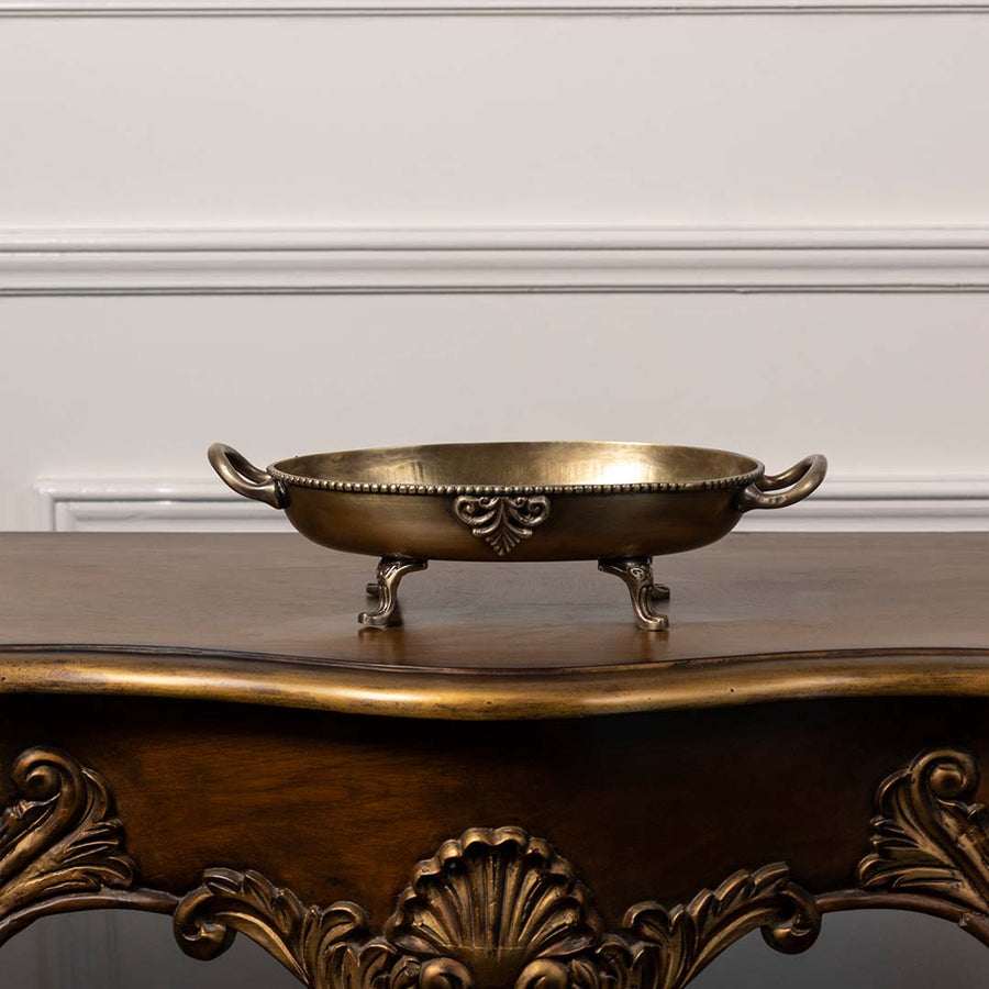 Antique style brass decorative bowl with ornate handles and carved legs perfect for table decor and luxury home styling.