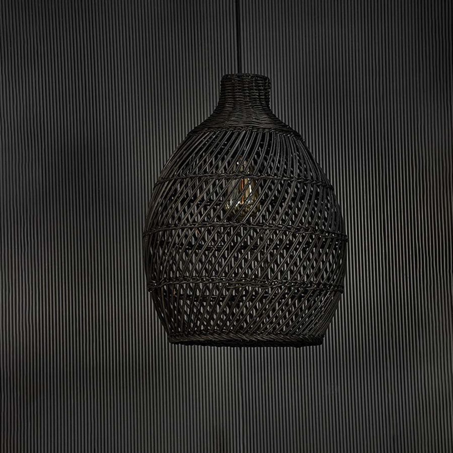 Contemporary black rattan pendant light against black background featuring handwoven texture and refined modern natural look.