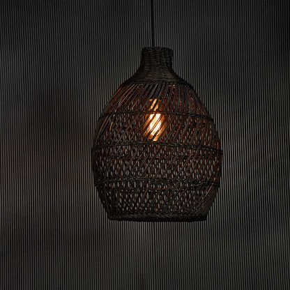 Elegant black rattan pendant lamp glowing on black background creating cozy lighting with woven design and artisanal feel.