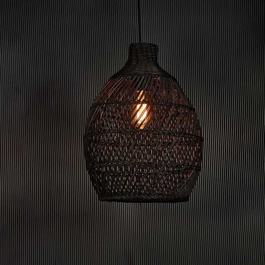 Elegant black rattan pendant lamp glowing on black background creating cozy lighting with woven design and artisanal feel.