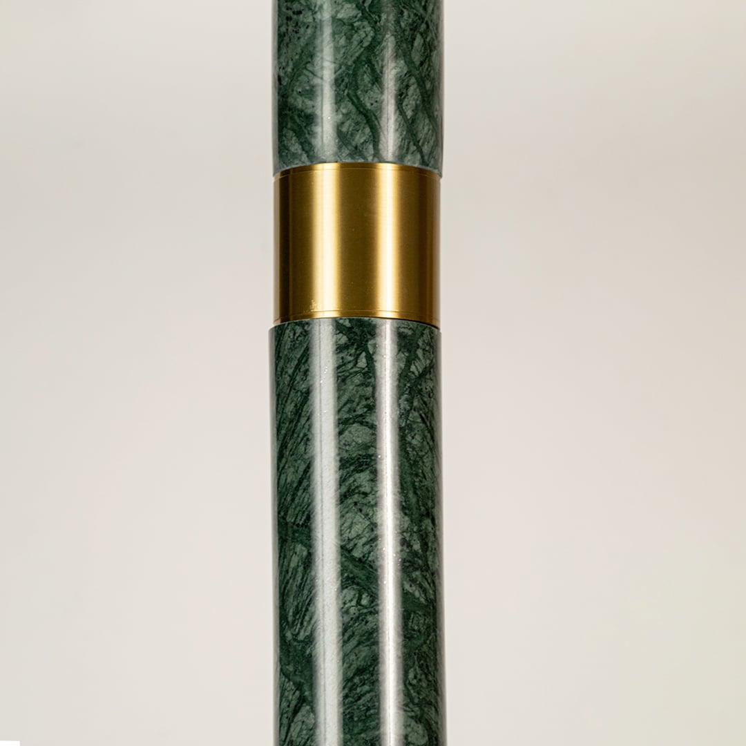 Green marble and metal long cylinder pendant light with clear bottom shown in close up view with light off for luxury modern décor.