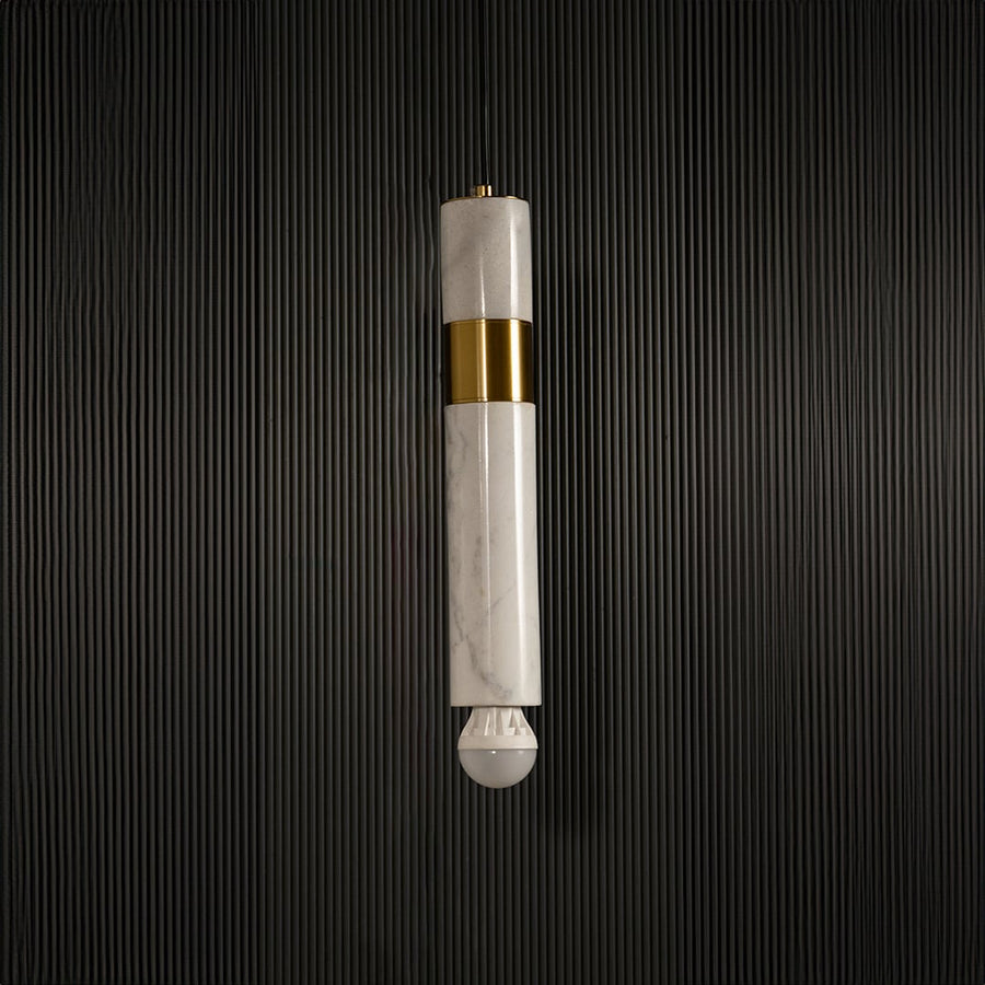White marble and metal cylinder pendant light with exposed bulb hanging against dark textured wall with light off for modern elegant décor.